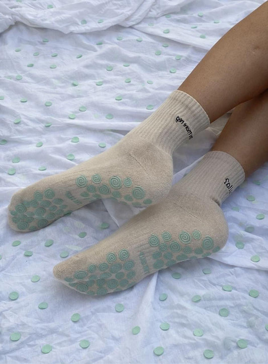 Person wearing beige socks with turquiose textured grips on the sole and Yalla One More Rep on the sock
